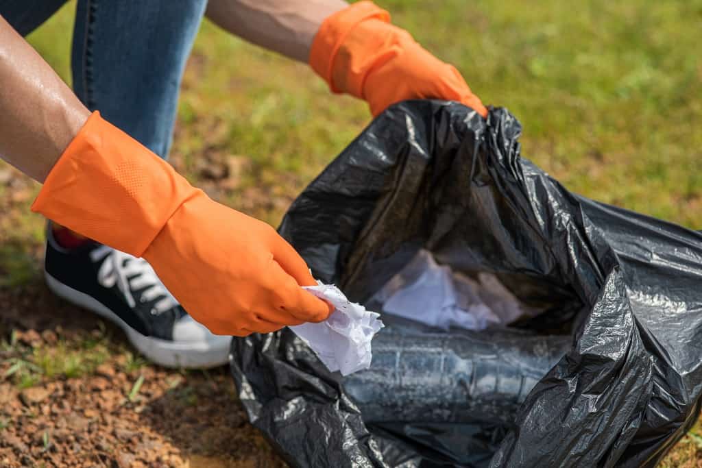 un homme porte des gants oranges et ramasse des déchets